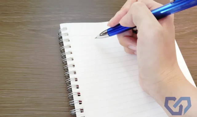 ノートにペンで書き込もうとしている