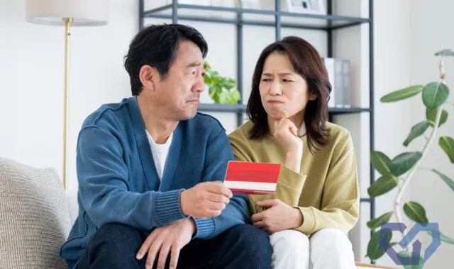 通帳を持って不安気な夫婦