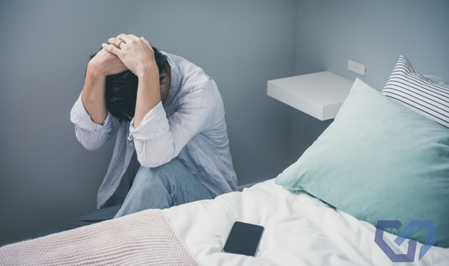 狭い部屋で頭を抱えている男性