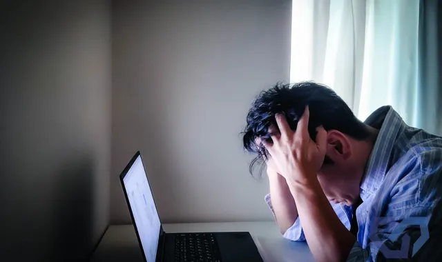 PCの前で頭を抱える男性